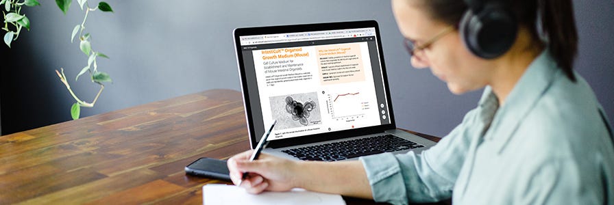 A researcher exploring content on Intesticult™ Organoid Growth Medium and taking notes.